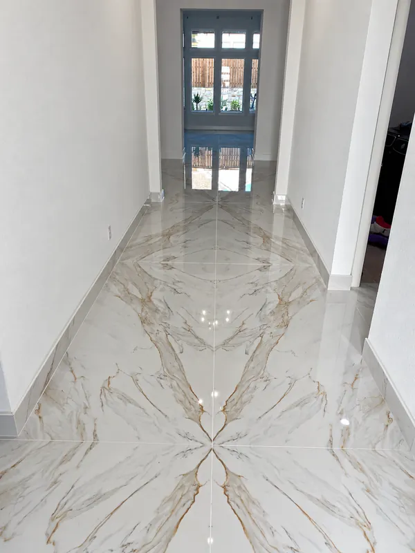 Installed polished white and gold-veined tile floor in an entry hallway