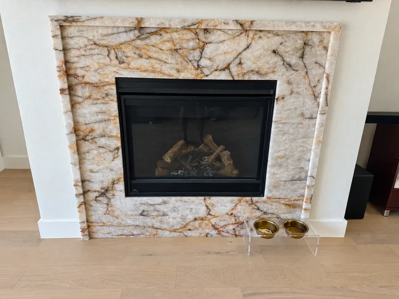 Installed light stone fireplace surround with gold and grey veining