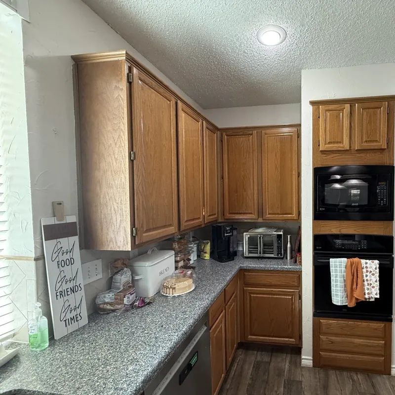 Before: kitchen with oak cabinets, granite countertops and black wall ovens