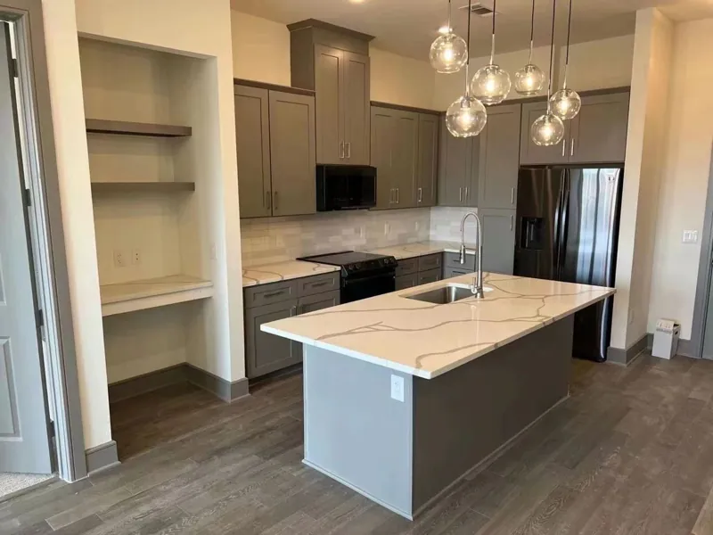 Kitchen with grey shaker cabinets and a white Calacatta-look quartz island, by Acue Marmonite