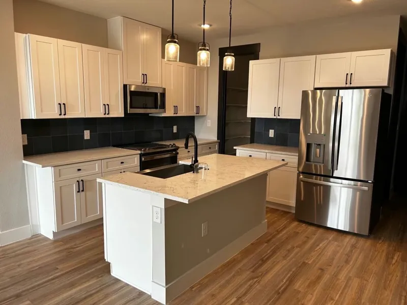 Kitchen with white shaker cabinets, dark tile backsplash and a grey island with quartz top, by Acue Marmonite