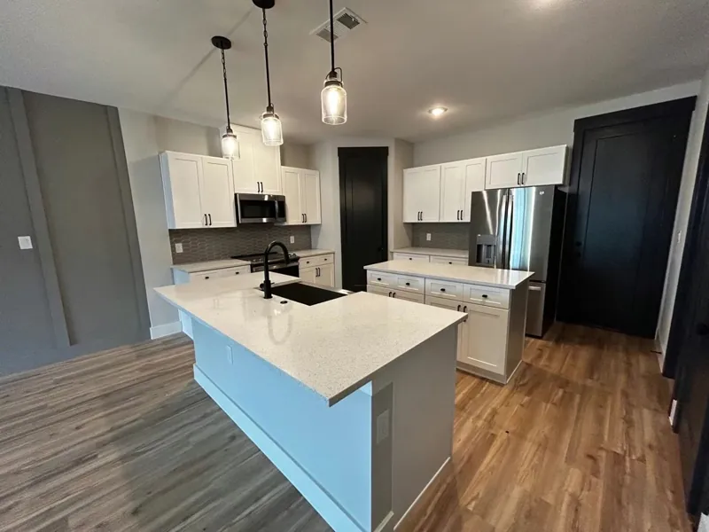 Kitchen with white shaker cabinets and a white quartz waterfall island, by Acue Marmonite