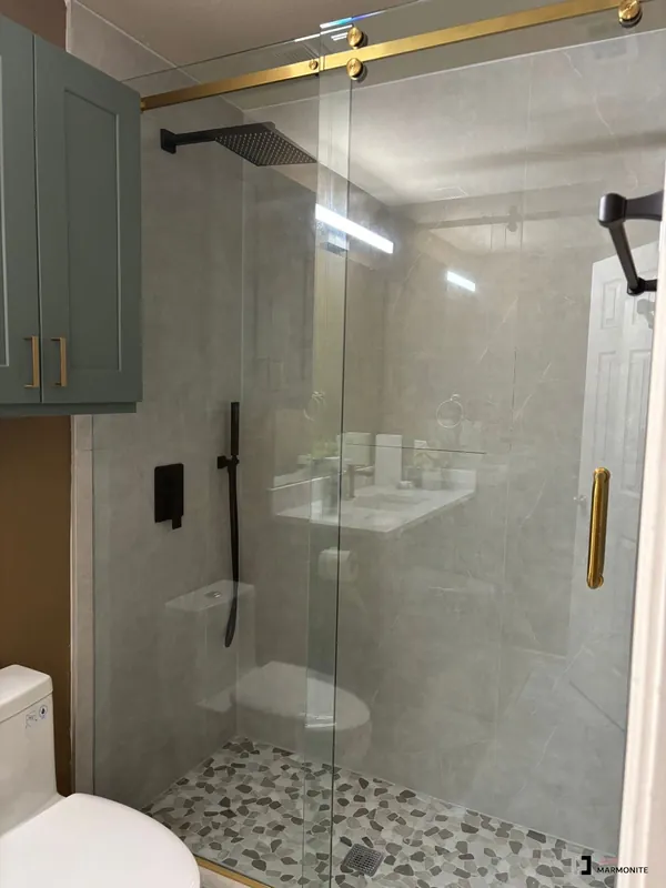 Frameless glass shower with marble tile and gold hardware