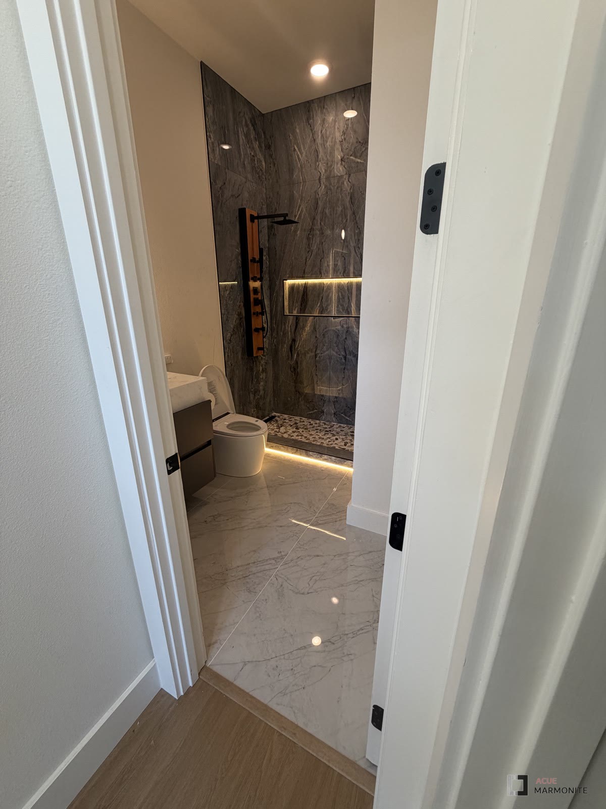 Bathroom remodel with dark natural stone shower wall, completed by Acue Marmonite