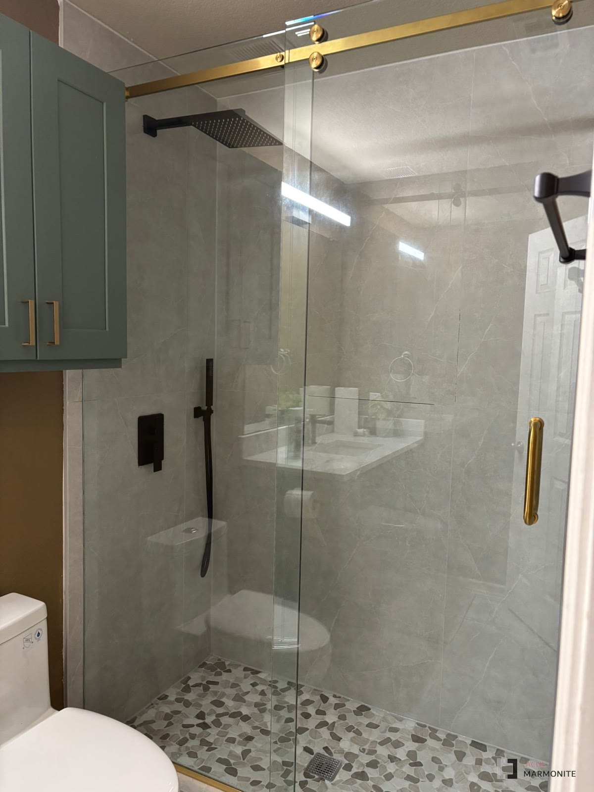Bathroom remodel with glass shower enclosure and sage cabinetry, completed by Acue Marmonite