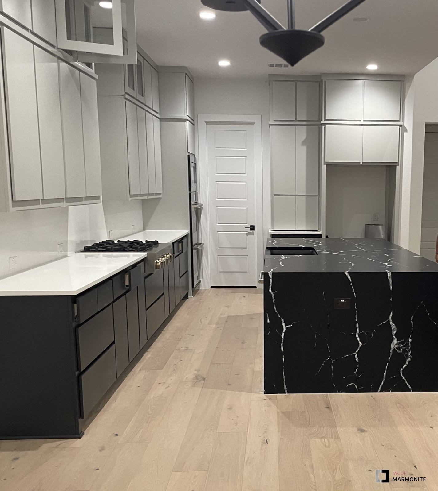 Black marble waterfall island with wide-plank floors