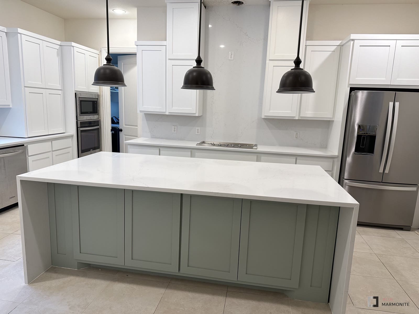 Kitchen remodel with white waterfall island and sage cabinets, completed by Acue Marmonite