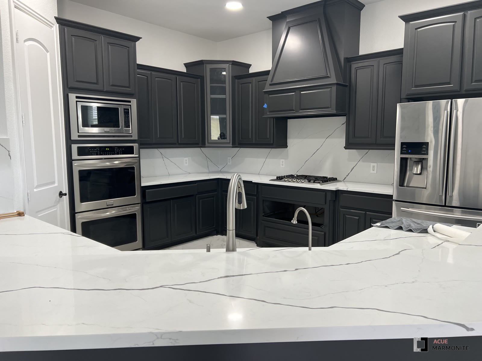 Full kitchen remodel with black cabinetry and marble backsplash