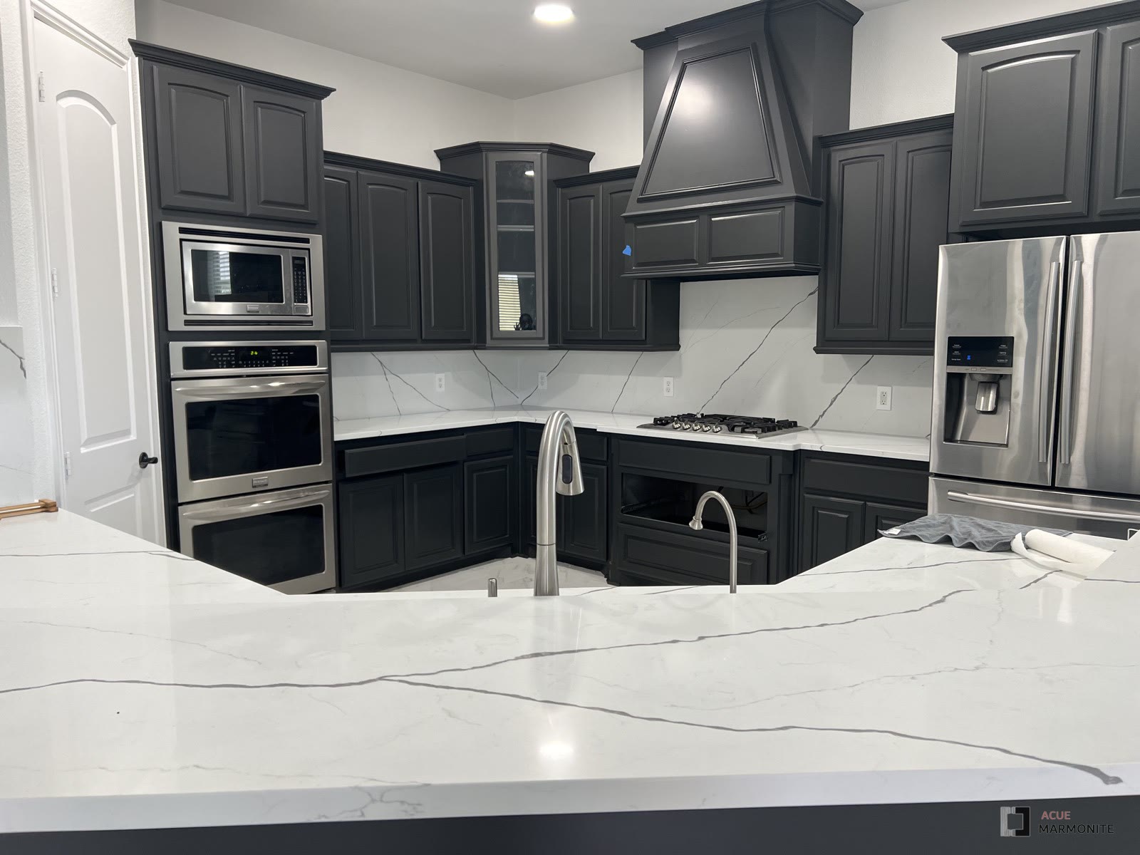 Kitchen remodel with dark cabinetry and quartz waterfall island, completed by Acue Marmonite