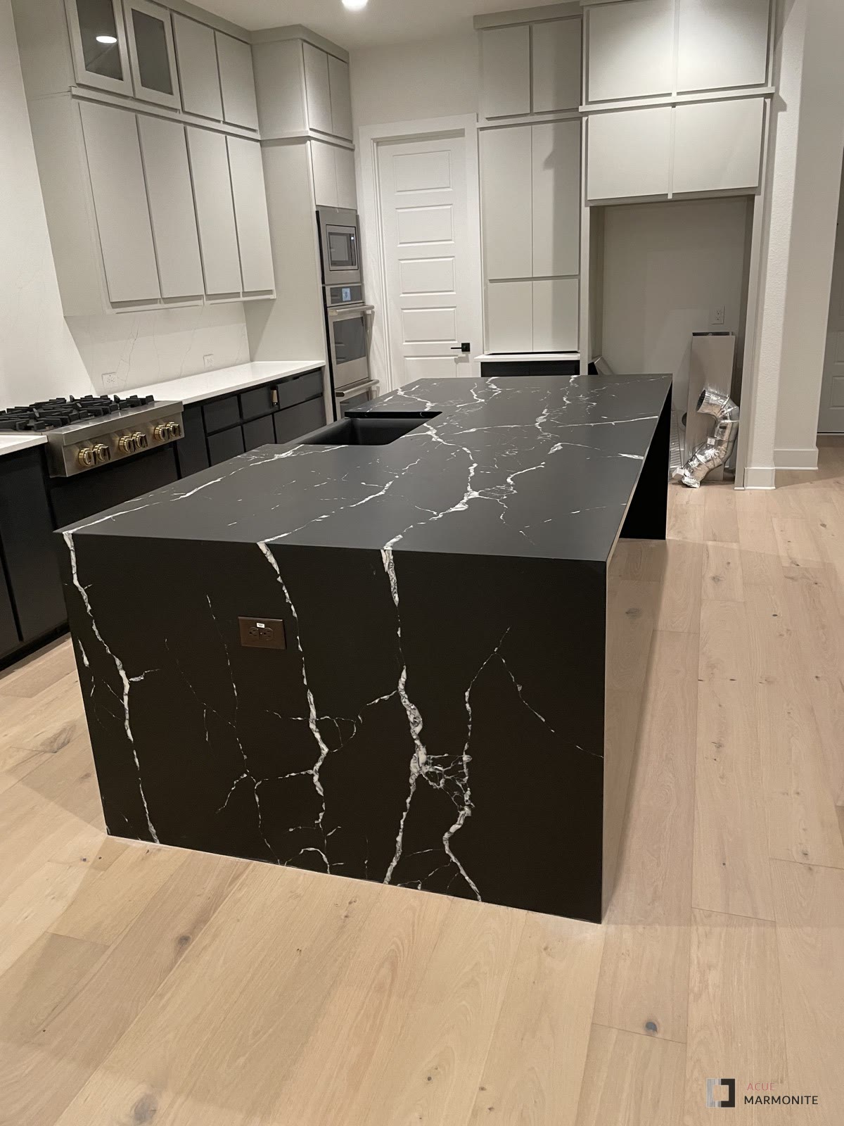 Kitchen remodel with black quartz waterfall island, completed by Acue Marmonite