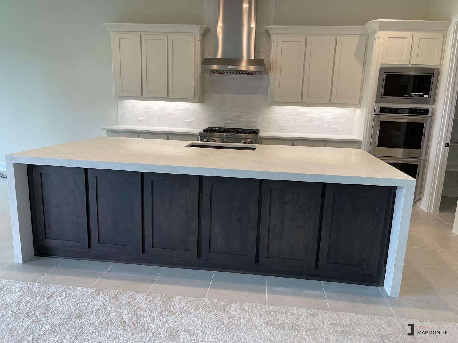 Calacatta Vesta quartz island with dark cabinetry, installed by Acue Marmonite