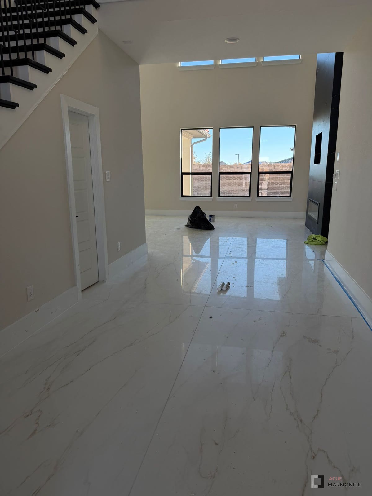 Large-format polished porcelain tile in an entry and living area, installed by Acue Marmonite